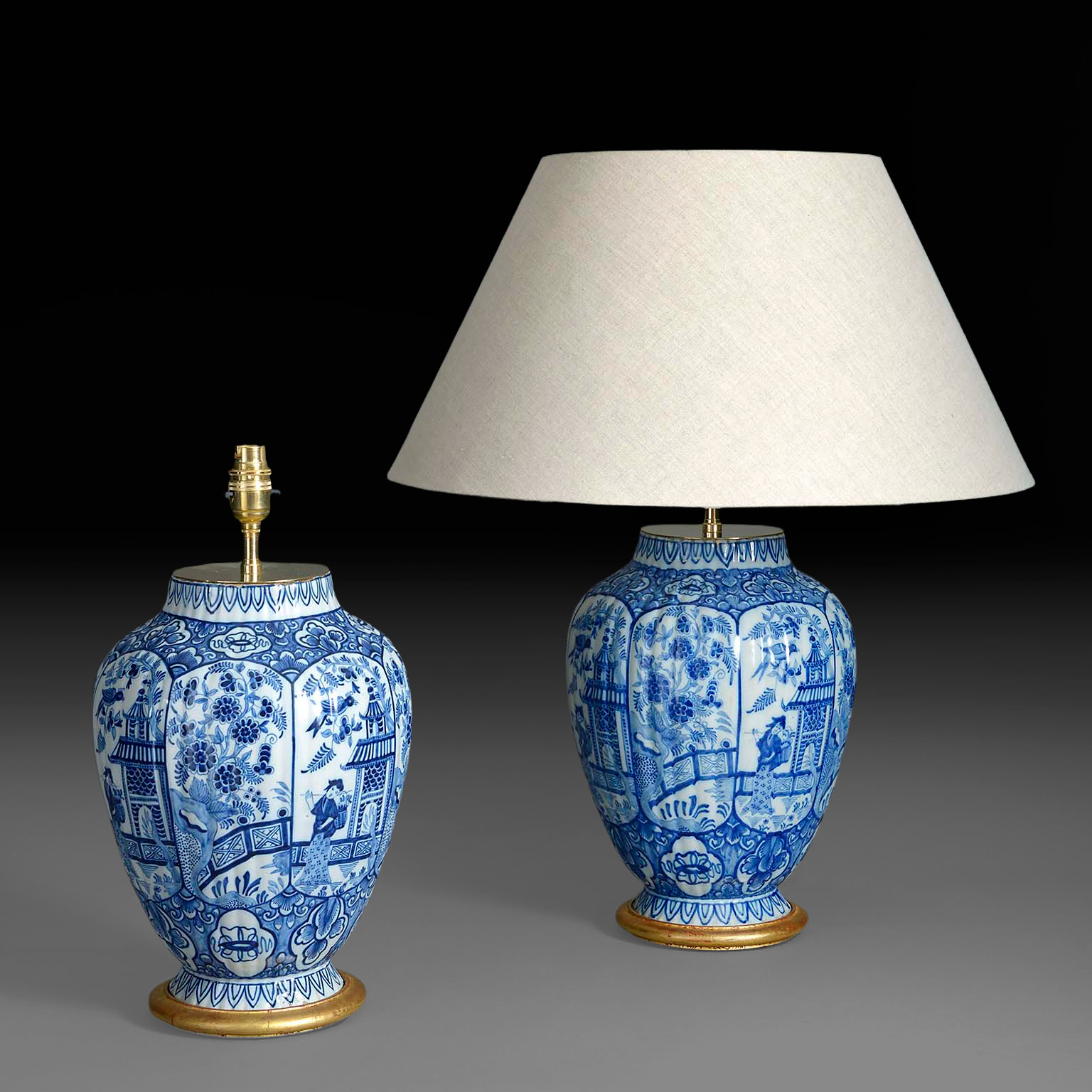 Pair of blue and white glazed antique Delft vase lamps with ribbed bodies and gilded bases, one with shade