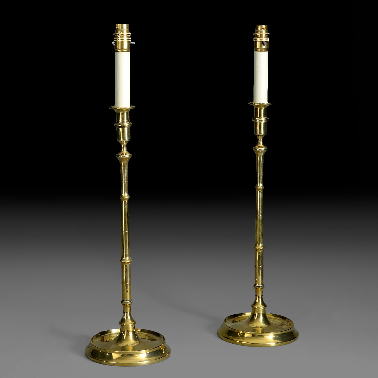 Pair of 19th century turned brass candlestick lamps without shades, showing faux painted candles and bulb holders